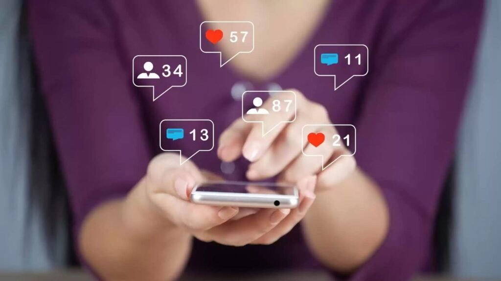 Pessoa utilizando smartphone com ícones de curtidas, comentários e seguidores representando o engajamento nas redes sociais – estratégia de timing da Agência Mais Resultado.