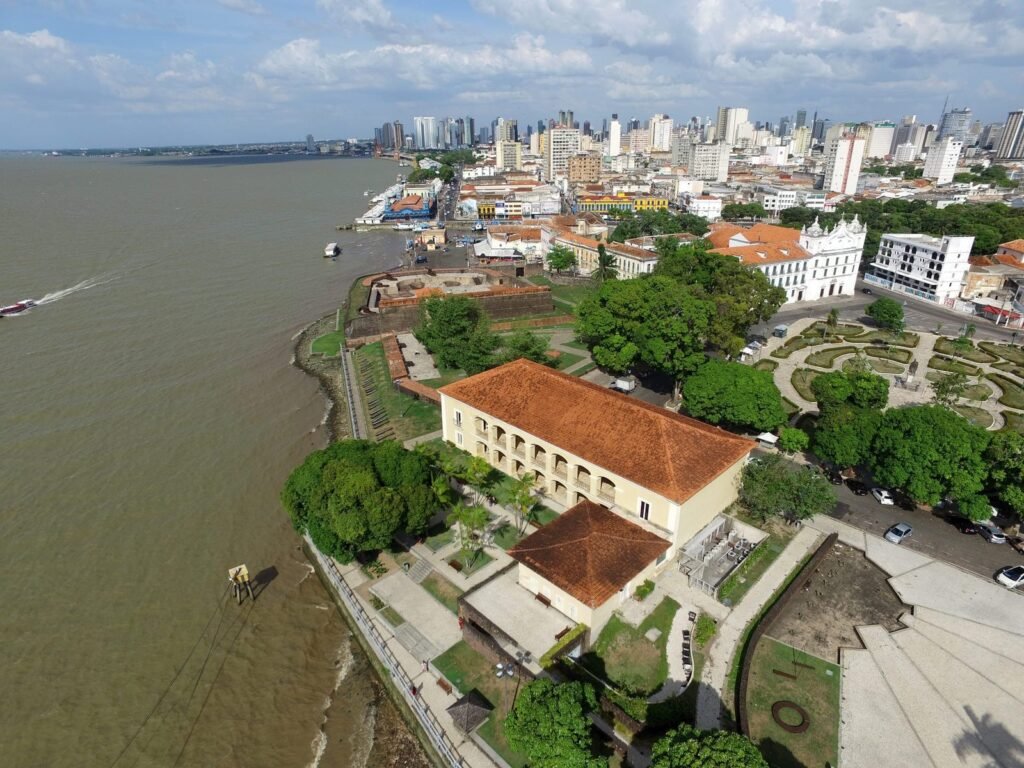 Vista aérea de Belém do Pará, mostrando prédios históricos, áreas verdes e o rio, destacando a beleza e o potencial empresarial da região.