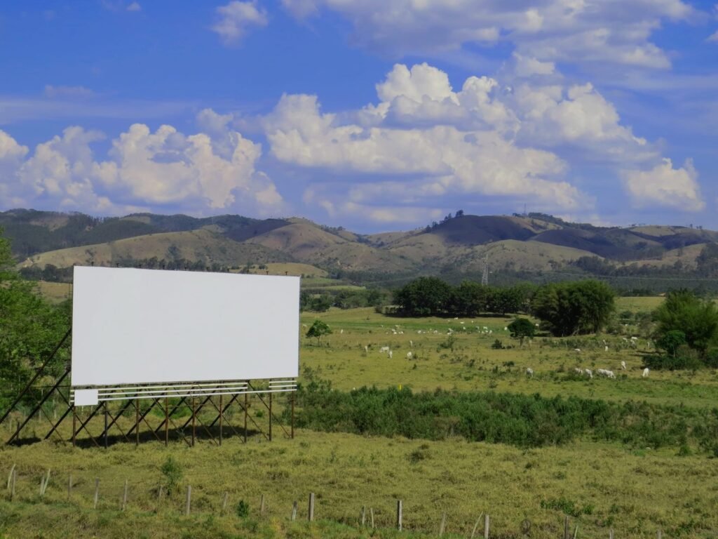 Outdoor branco instalado em área rural com paisagem de colinas ao fundo, ilustrando a relevância do marketing offline mesmo na era digital.
