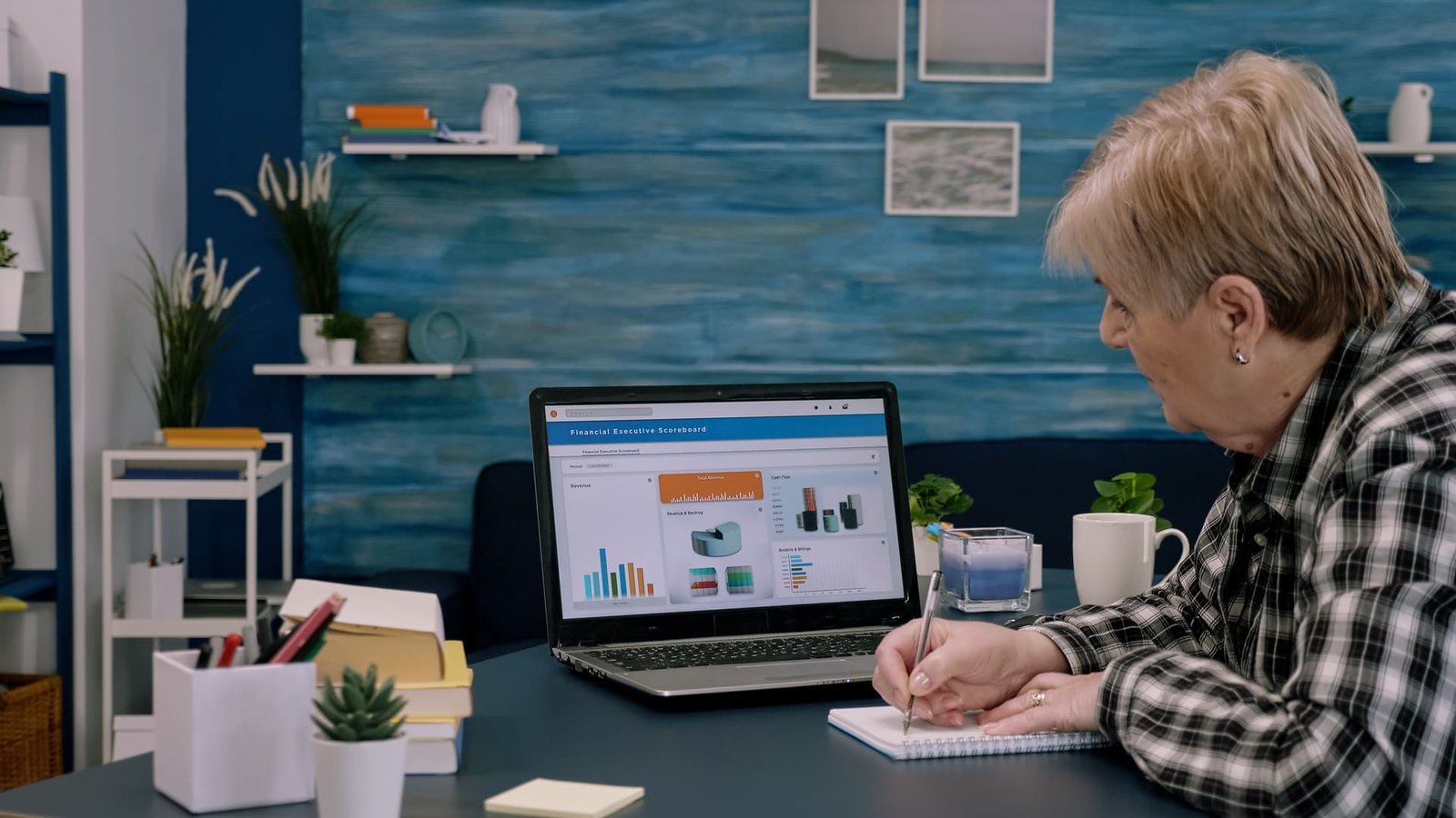 Empresária analisando gráficos de desempenho no laptop enquanto faz anotações, simbolizando otimização de sites para conversão e melhorias em estratégias digitais.