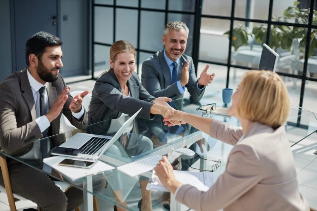 Reunião de empresários em ambiente corporativo celebrando acordo de franquia com aperto de mãos — estratégia de expansão com a Agência Mais Resultado.