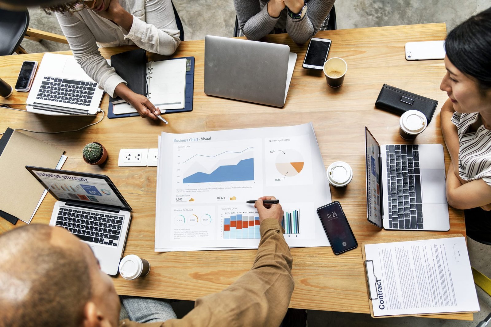 Grupo diverso de pessoas reunidas em uma mesa, analisando gráficos e planejando estratégias de SEO e marketing digital para otimizar resultados online.