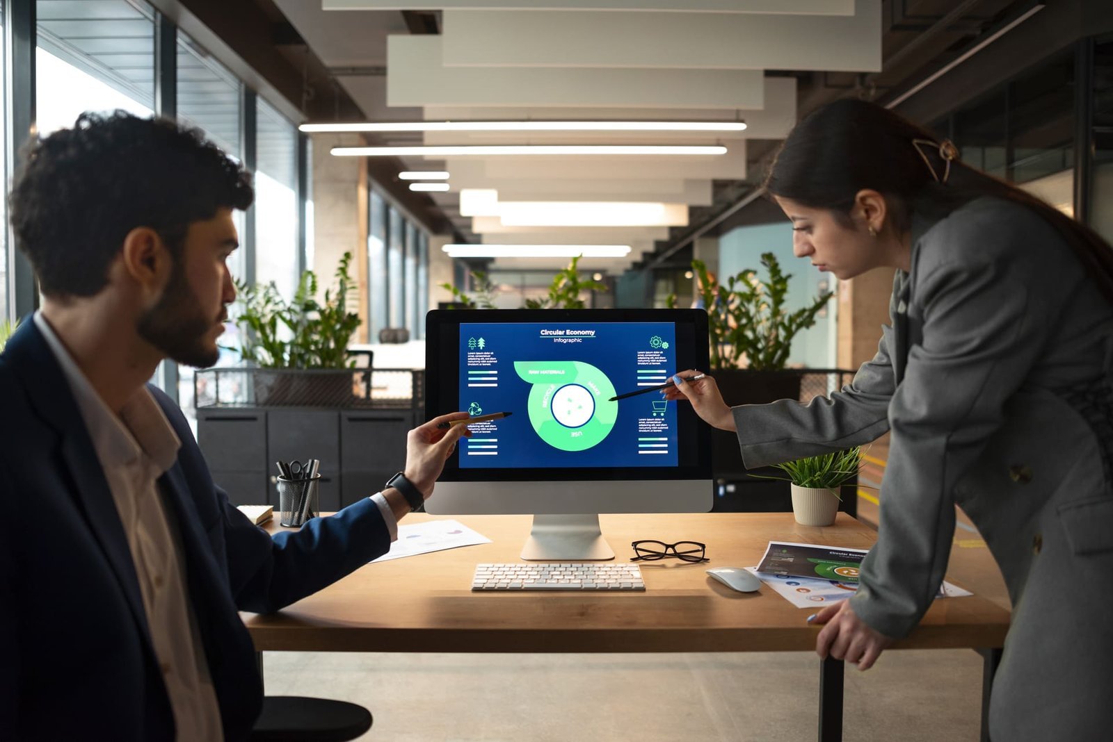 Duas pessoas em um escritório discutindo estratégias de automação de marketing com gráficos em um monitor. O ambiente moderno e profissional reflete a colaboração e análise de dados para decisões assertivas.