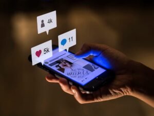 Pessoa segurando smartphone com interações de curtidas, comentários e seguidores em destaque, representando engajamento em campanhas de captação de leads no Instagram e Facebook pela Agência Mais Resultado.
