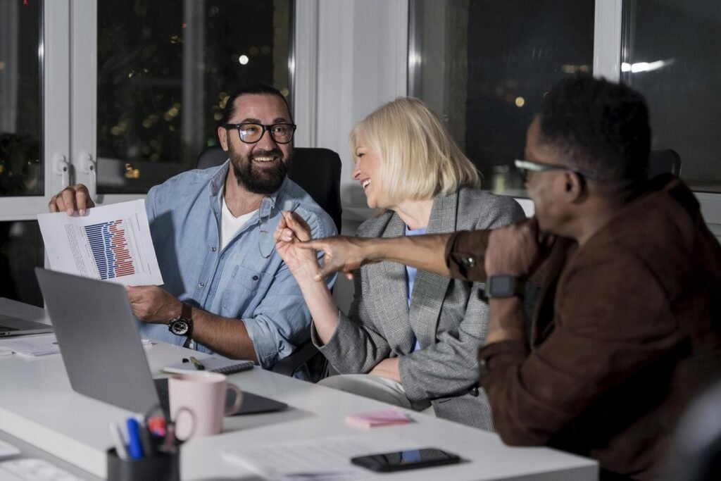 Equipe discutindo estratégias e resultados em reunião noturna no escritório com gráficos e laptop na mesa.