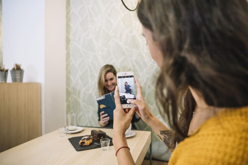 Pessoa tirando foto de amiga com celular em um ambiente descontraído, representando o uso criativo de redes sociais como o TikTok para marketing.